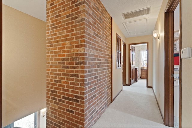 hallway featuring visible vents, light colored carpet, attic access, and baseboards