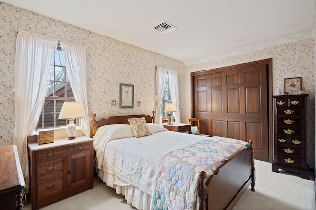 bedroom featuring visible vents, wallpapered walls, light carpet, multiple windows, and a closet