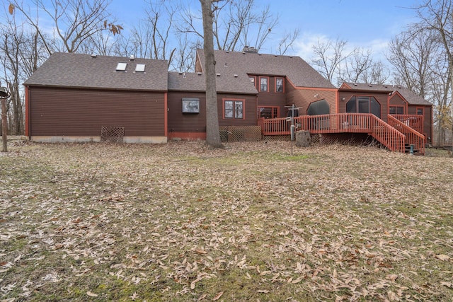 back of house featuring a wooden deck and roof with shingles