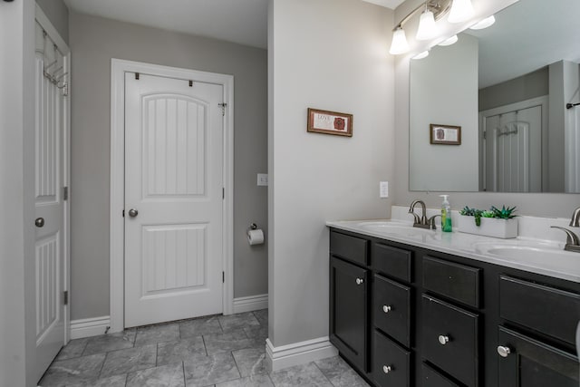 bathroom with double vanity, baseboards, and a sink