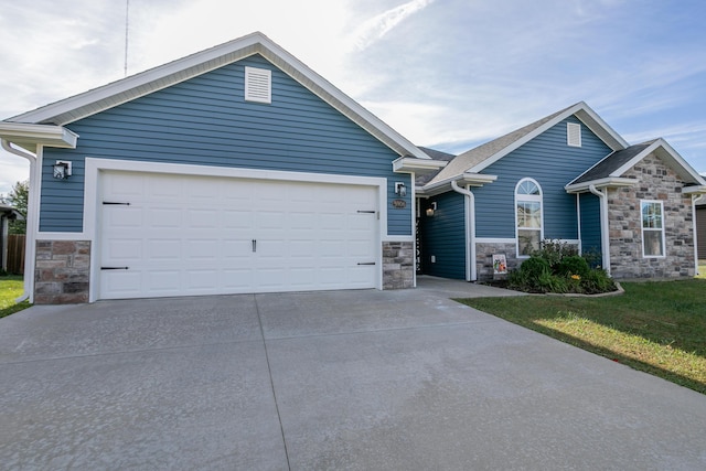 view of front of home featuring stone siding, a garage, driveway, and a front lawn