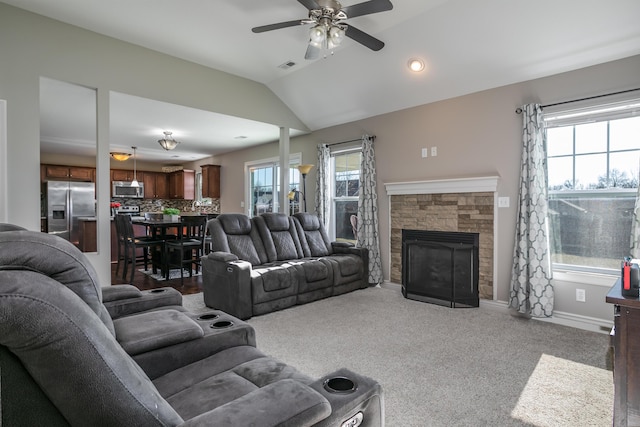 living room with a stone fireplace, visible vents, plenty of natural light, and lofted ceiling