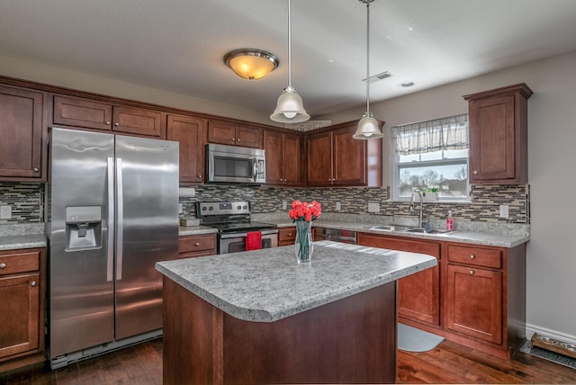 kitchen with a sink, dark wood-type flooring, light countertops, appliances with stainless steel finishes, and decorative light fixtures