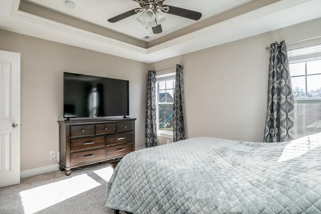 carpeted bedroom with a tray ceiling, baseboards, and a ceiling fan