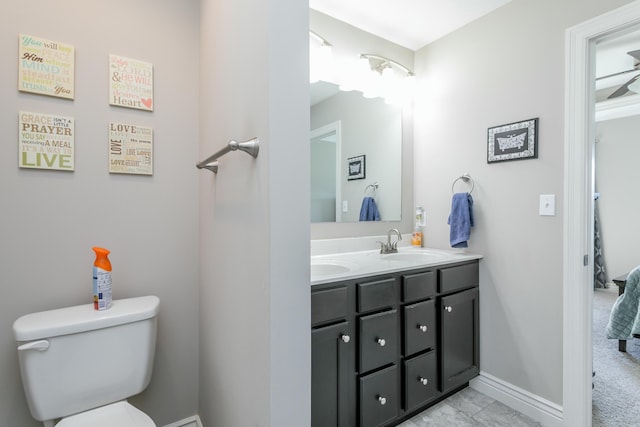 bathroom featuring a sink, baseboards, toilet, and double vanity