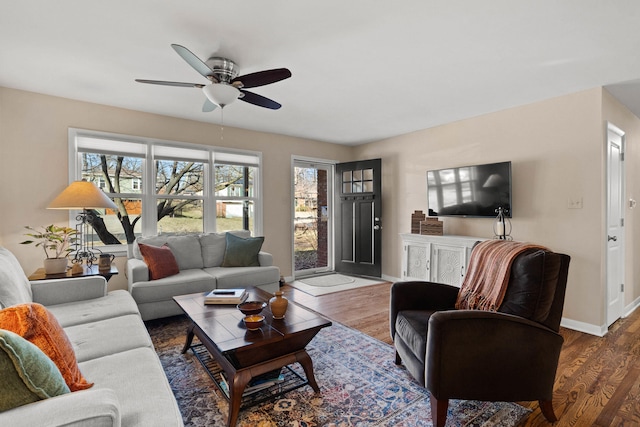 living room with a ceiling fan, baseboards, and wood finished floors