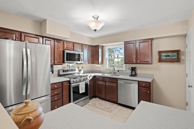 kitchen featuring light tile patterned flooring, stainless steel appliances, a sink, and light countertops