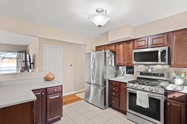 kitchen with appliances with stainless steel finishes, light countertops, baseboards, and light tile patterned flooring