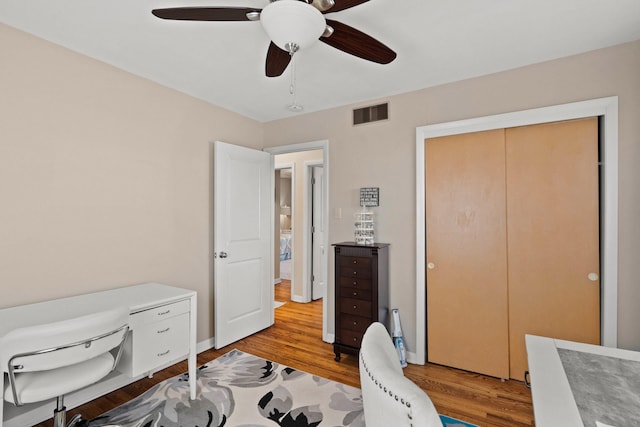 office space with a ceiling fan, baseboards, visible vents, and wood finished floors