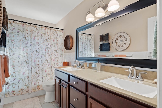 bathroom featuring double vanity, a sink, toilet, and tile patterned floors