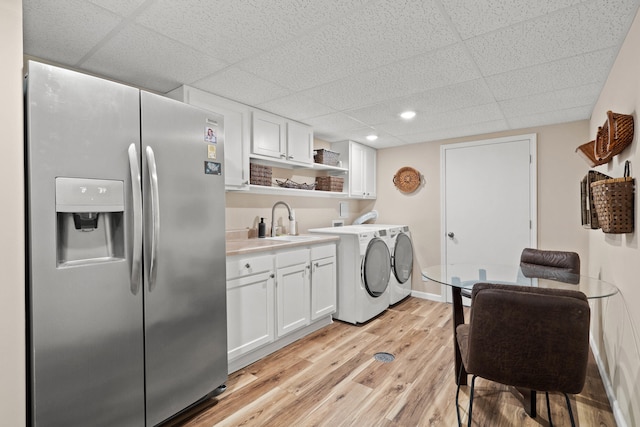 laundry area with light wood finished floors, baseboards, washing machine and clothes dryer, a sink, and recessed lighting