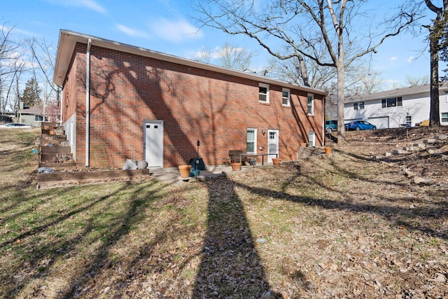 rear view of property with brick siding and a lawn