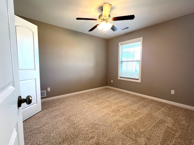 carpeted spare room with visible vents, ceiling fan, and baseboards