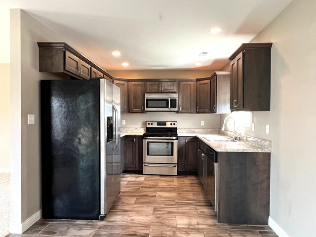 kitchen featuring stainless steel appliances, light countertops, visible vents, a sink, and dark brown cabinetry