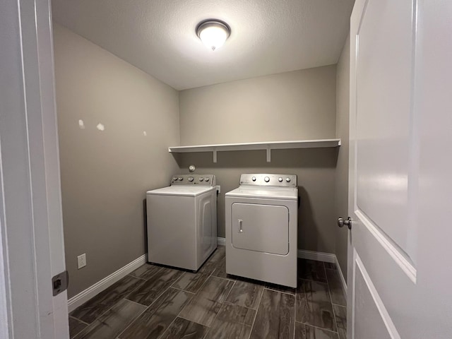 laundry area with wood tiled floor, a textured ceiling, washer and dryer, laundry area, and baseboards