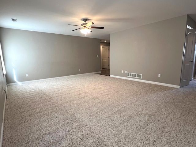 carpeted spare room with baseboards, visible vents, and a ceiling fan