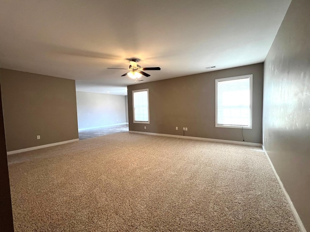 carpeted empty room featuring ceiling fan and baseboards