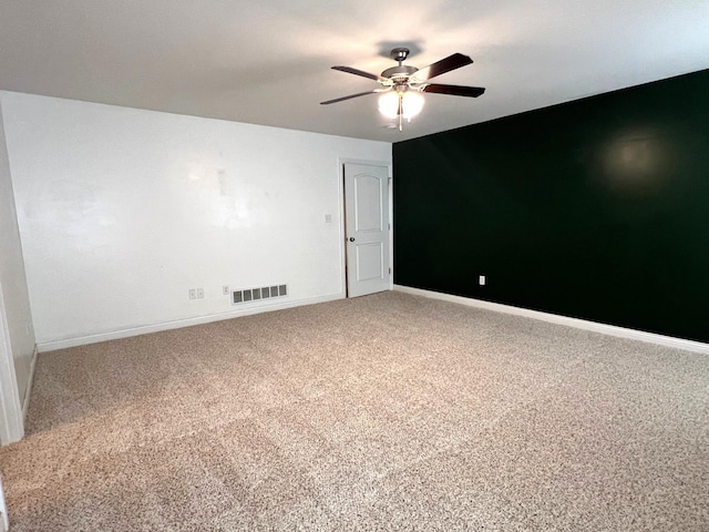 spare room with baseboards, carpet floors, visible vents, and a ceiling fan