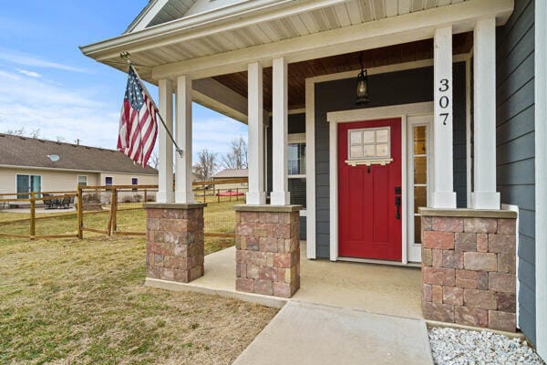 doorway to property with a yard, a porch, and fence