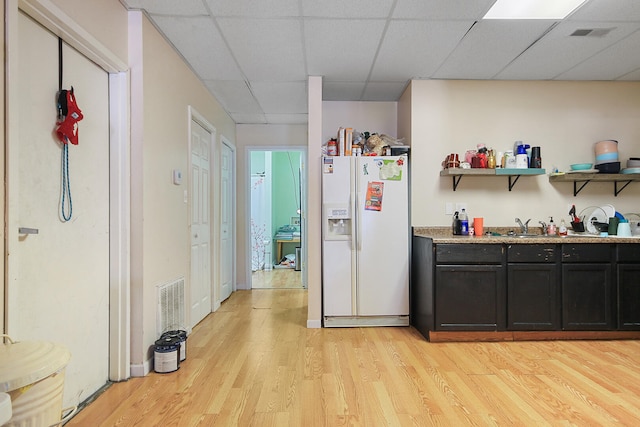 bar with visible vents, a paneled ceiling, light wood-type flooring, and white fridge with ice dispenser