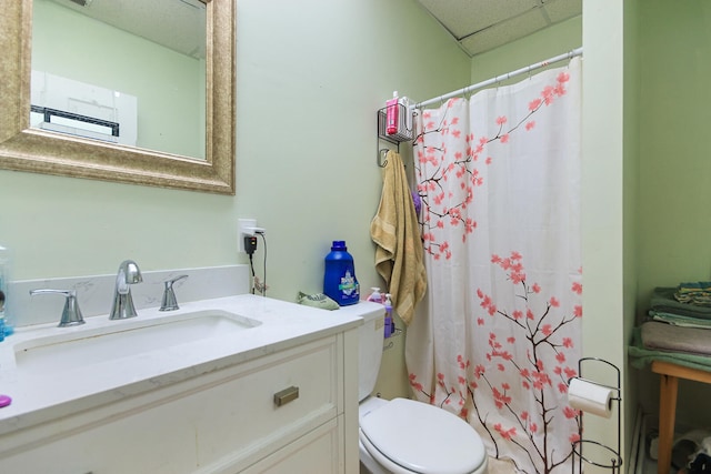 bathroom featuring vanity, curtained shower, toilet, and a drop ceiling