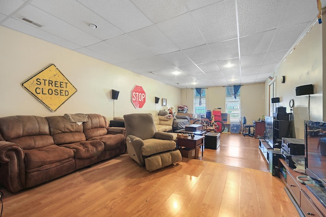 living room featuring light wood-style floors, visible vents, and a paneled ceiling