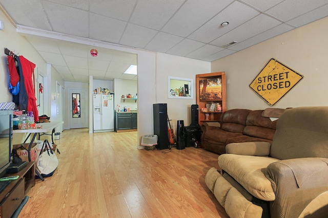 living area with light wood-style floors, visible vents, and a paneled ceiling