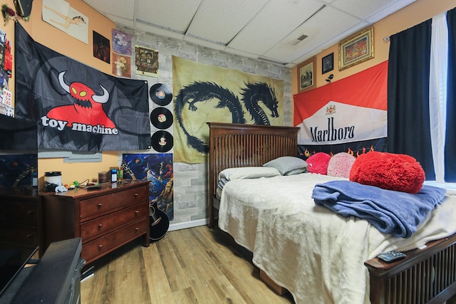 bedroom featuring wood finished floors, a paneled ceiling, baseboards, and visible vents