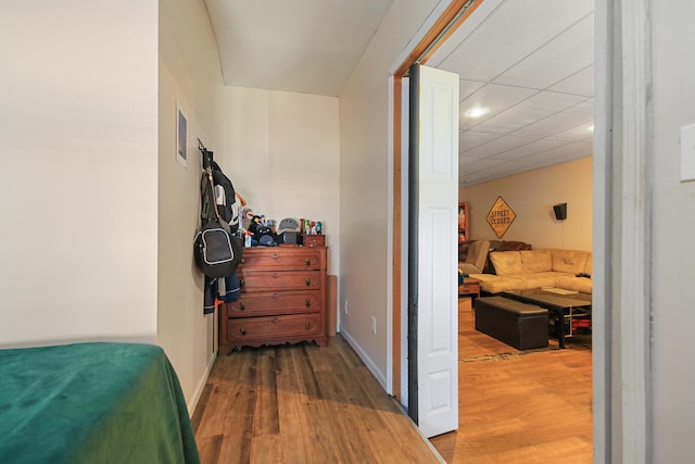 bedroom featuring a paneled ceiling, baseboards, and wood finished floors