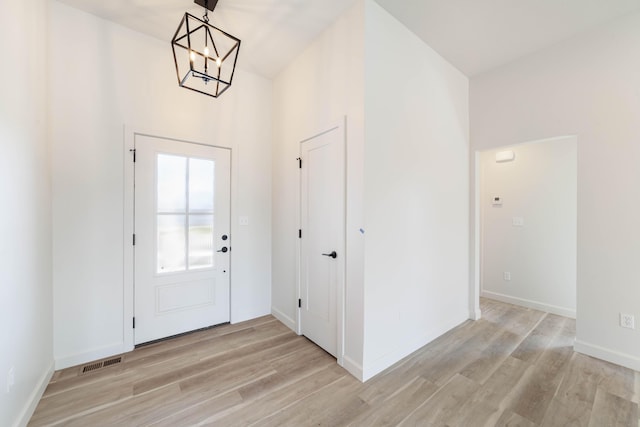 foyer with an inviting chandelier, baseboards, visible vents, and light wood finished floors