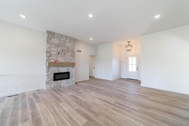 unfurnished living room with recessed lighting, visible vents, a stone fireplace, and light wood finished floors