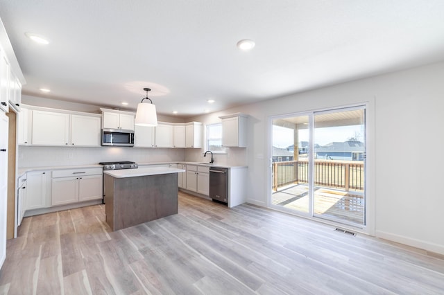 kitchen featuring visible vents, backsplash, light wood-style flooring, stainless steel appliances, and a sink