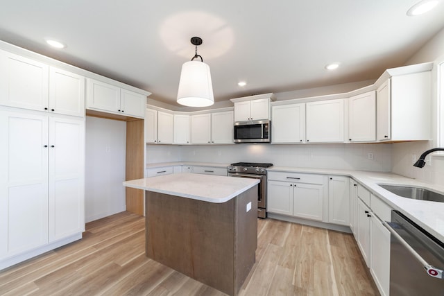 kitchen featuring a sink, light wood-style flooring, white cabinetry, and stainless steel appliances