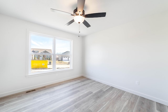 spare room with visible vents, light wood-style flooring, baseboards, and ceiling fan