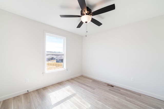 unfurnished room featuring light wood finished floors, visible vents, and baseboards