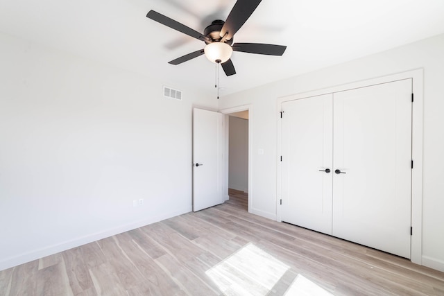 unfurnished bedroom with a ceiling fan, visible vents, baseboards, light wood-style floors, and a closet