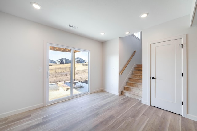 unfurnished room featuring light wood finished floors, visible vents, baseboards, stairs, and recessed lighting