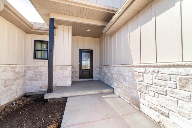 view of exterior entry with stone siding and board and batten siding