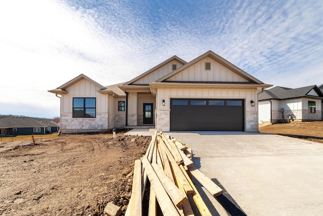 view of front of property featuring stone siding, board and batten siding, concrete driveway, and a garage