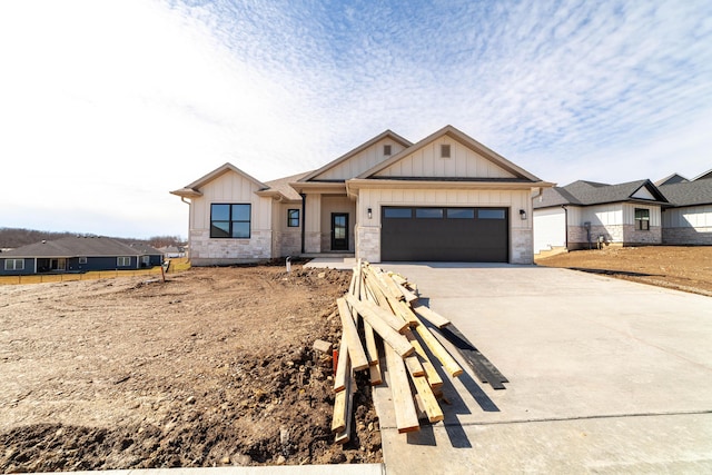 modern farmhouse style home featuring a garage, stone siding, board and batten siding, and driveway