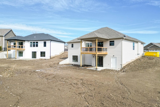 rear view of property featuring a balcony and roof with shingles