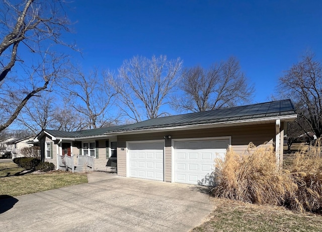 view of front facade with driveway, a standing seam roof, covered porch, a garage, and metal roof