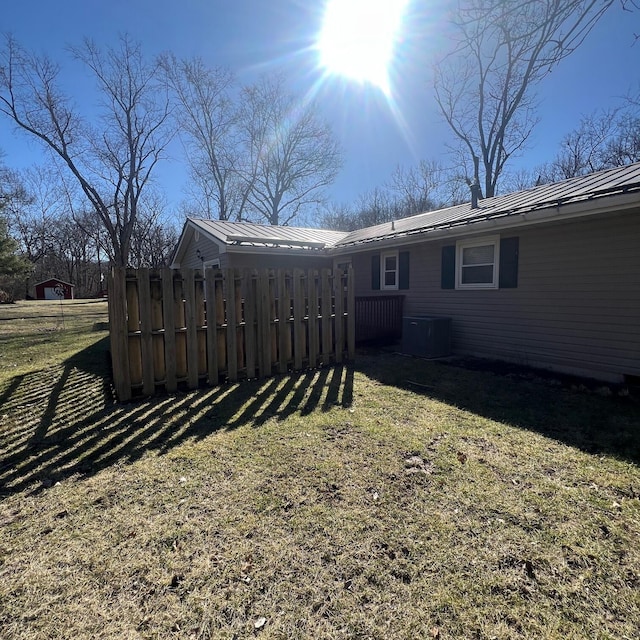 back of house featuring fence, a lawn, central AC, and metal roof