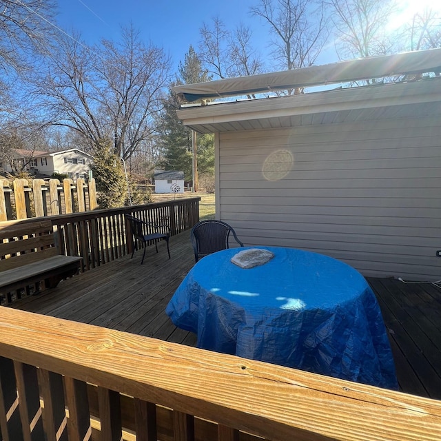 wooden terrace featuring a shed, outdoor dining area, and an outdoor structure