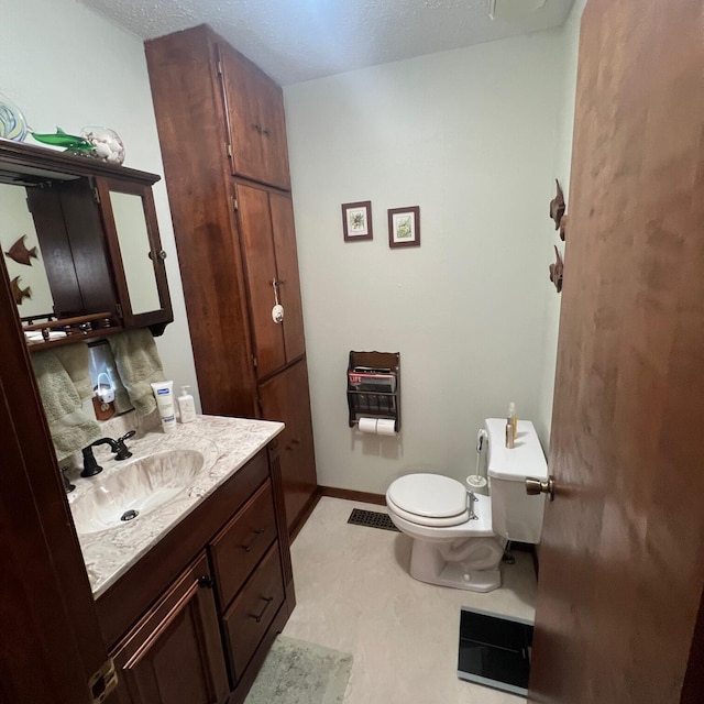 bathroom with baseboards, toilet, vanity, heating unit, and a textured ceiling