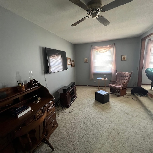 living area featuring baseboards, light carpet, a textured ceiling, and ceiling fan