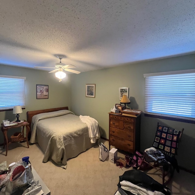 bedroom with ceiling fan, carpet, and a textured ceiling