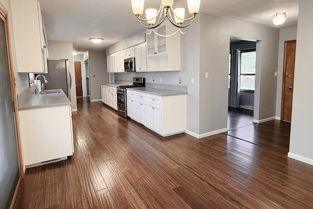 kitchen with a sink, dark wood-style floors, appliances with stainless steel finishes, light countertops, and baseboards