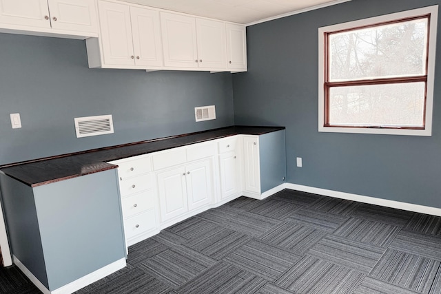 kitchen featuring dark countertops, visible vents, baseboards, white cabinetry, and dark colored carpet