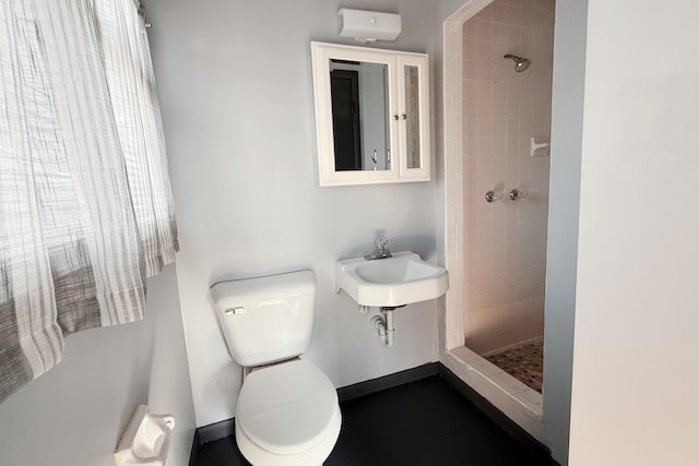 bathroom featuring a shower stall, toilet, and baseboards